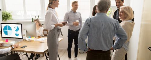 smiling-happy-young-and-senior-office-workers-talking-in-coworking